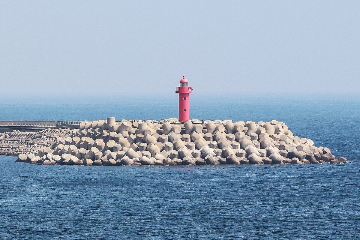 lighthouse on south island with mountain backdrop