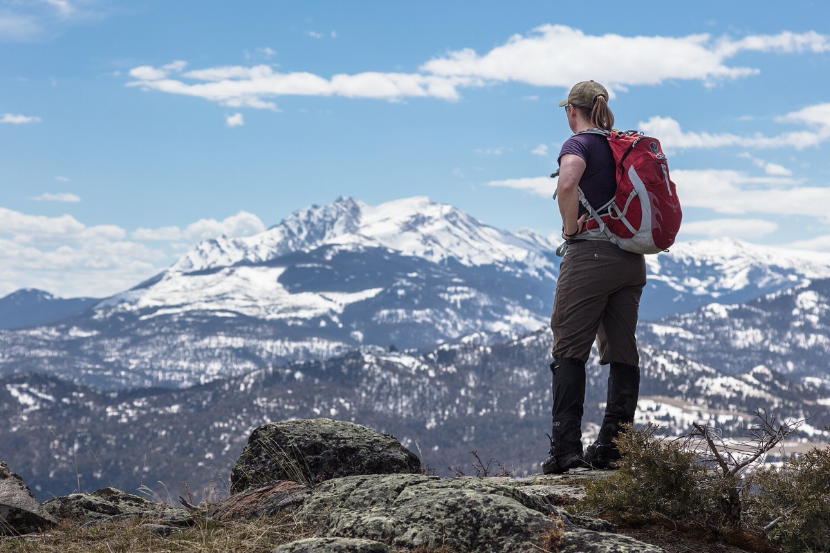 Hiker standing on mountain peak with panoramic view of New Zealand