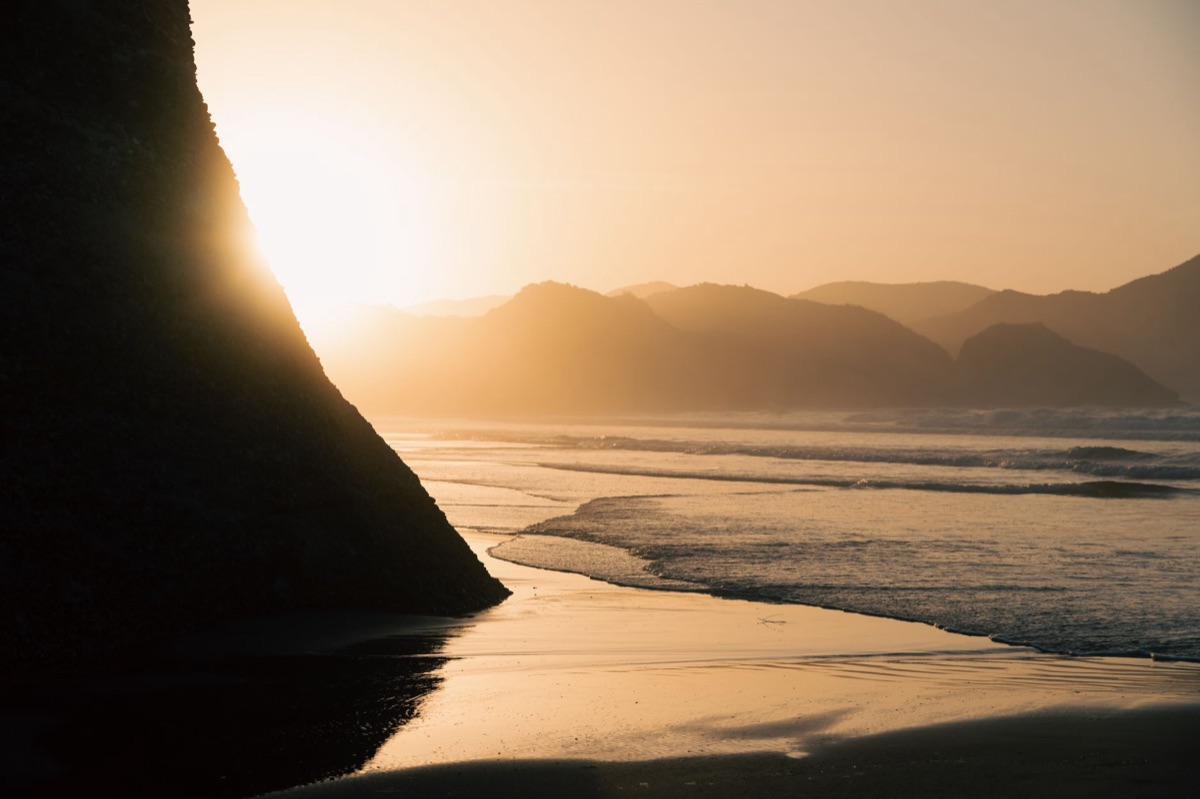 New Zealand coastline at dawn with misty mountains in the distance