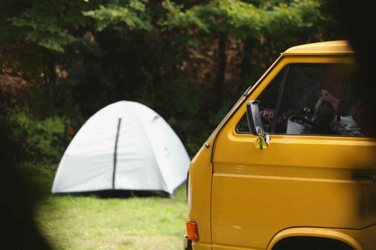 Camping van with tent and gear rack in scenic mountain landscape
