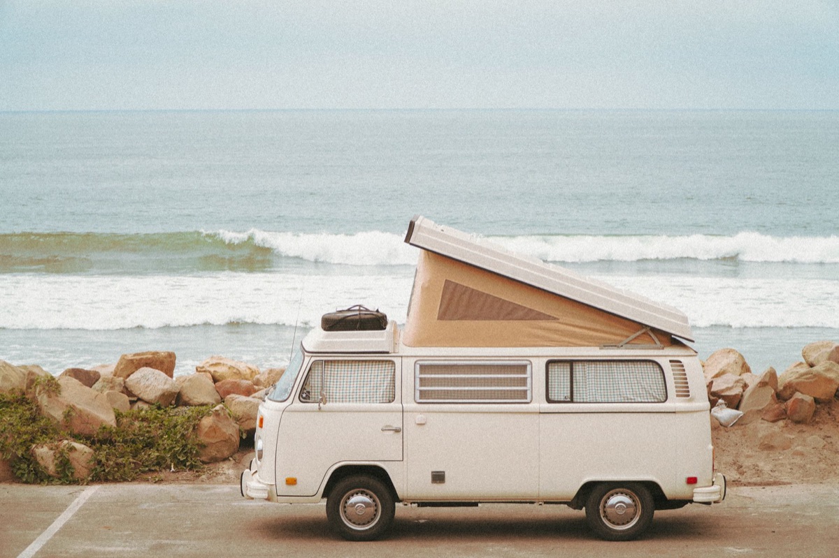 Camping van parked on beach with luggage and hiking gear