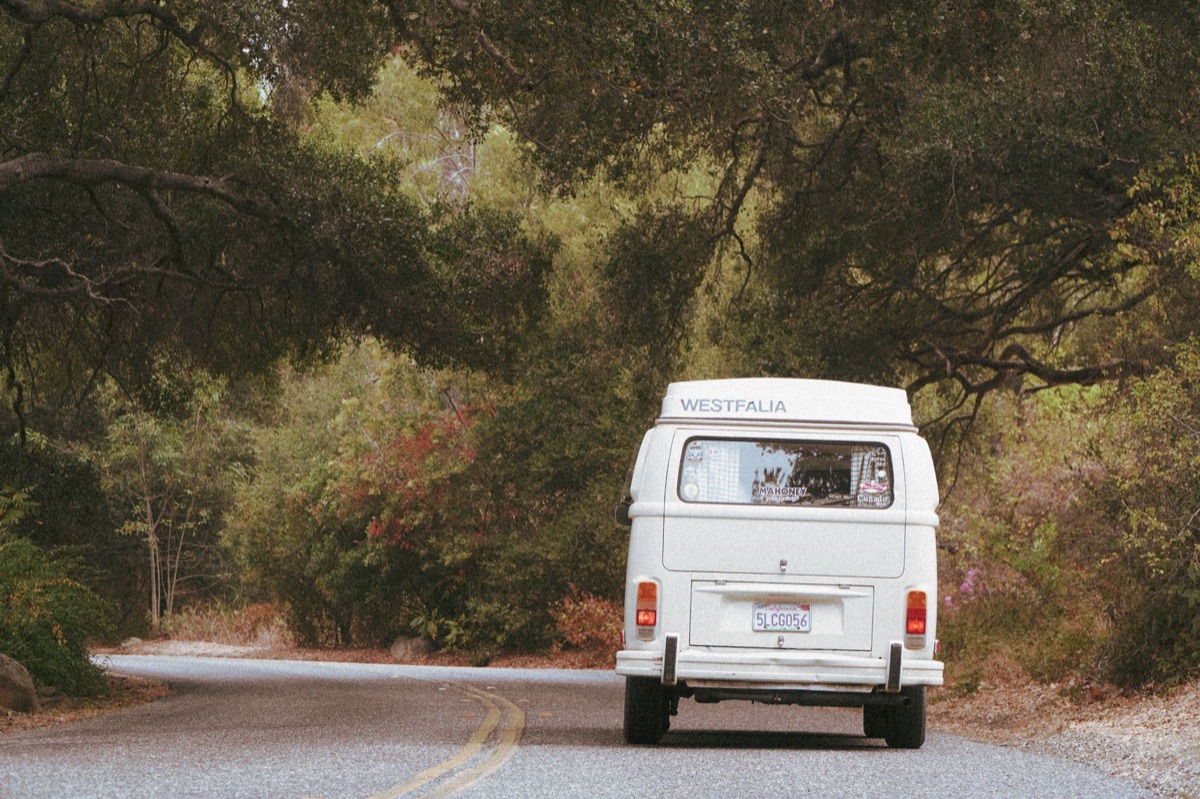 camper van on gravel road with forest in background
