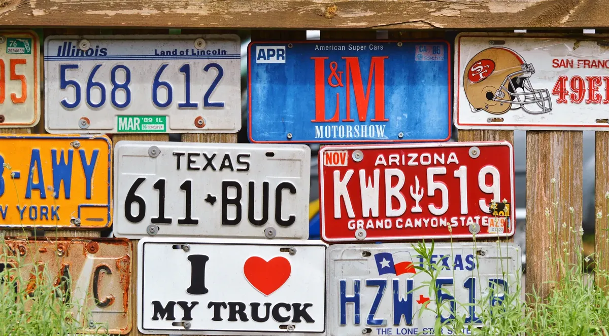 Decorative display of vintage American license plates on a rustic wooden fence.