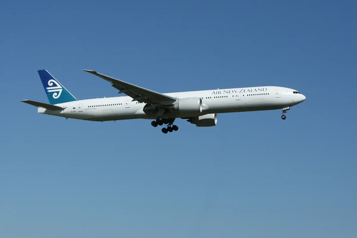 Air New Zealand Boeing 777 airliner flying against a clear blue sky, showcasing aviation travel.